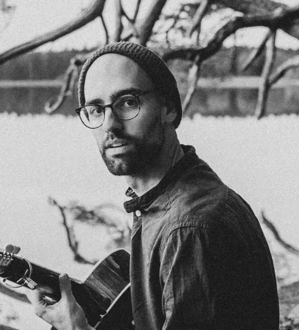 Mann mit Gitarre schaut in die Kamera