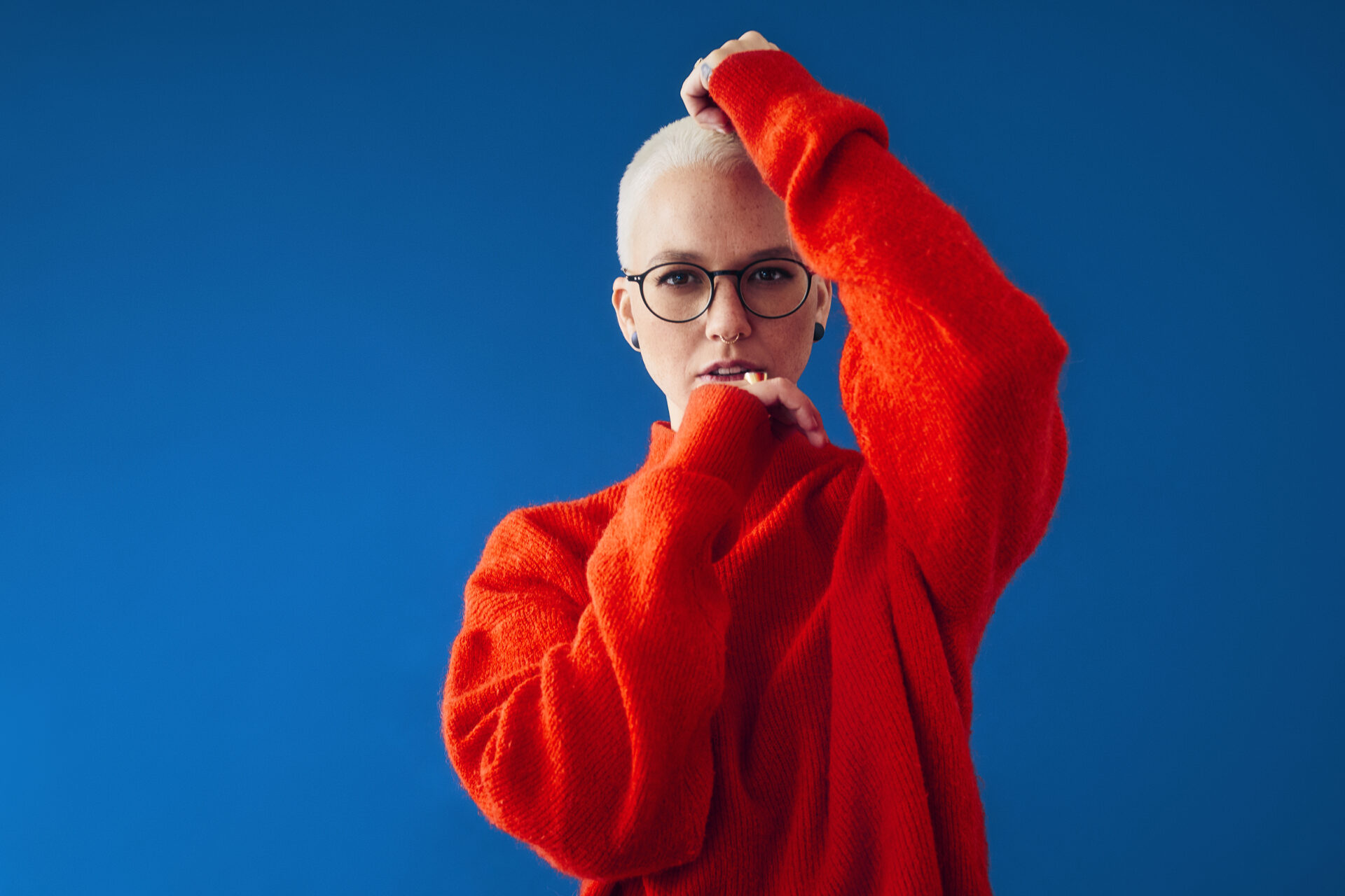 Stefanie Heinzmann steht im roten Pullover vor blauer Wand