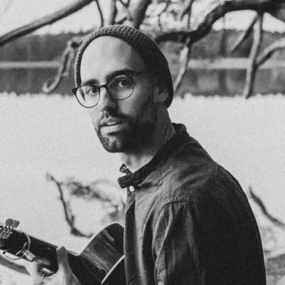 Mann mit Gitarre schaut in die Kamera